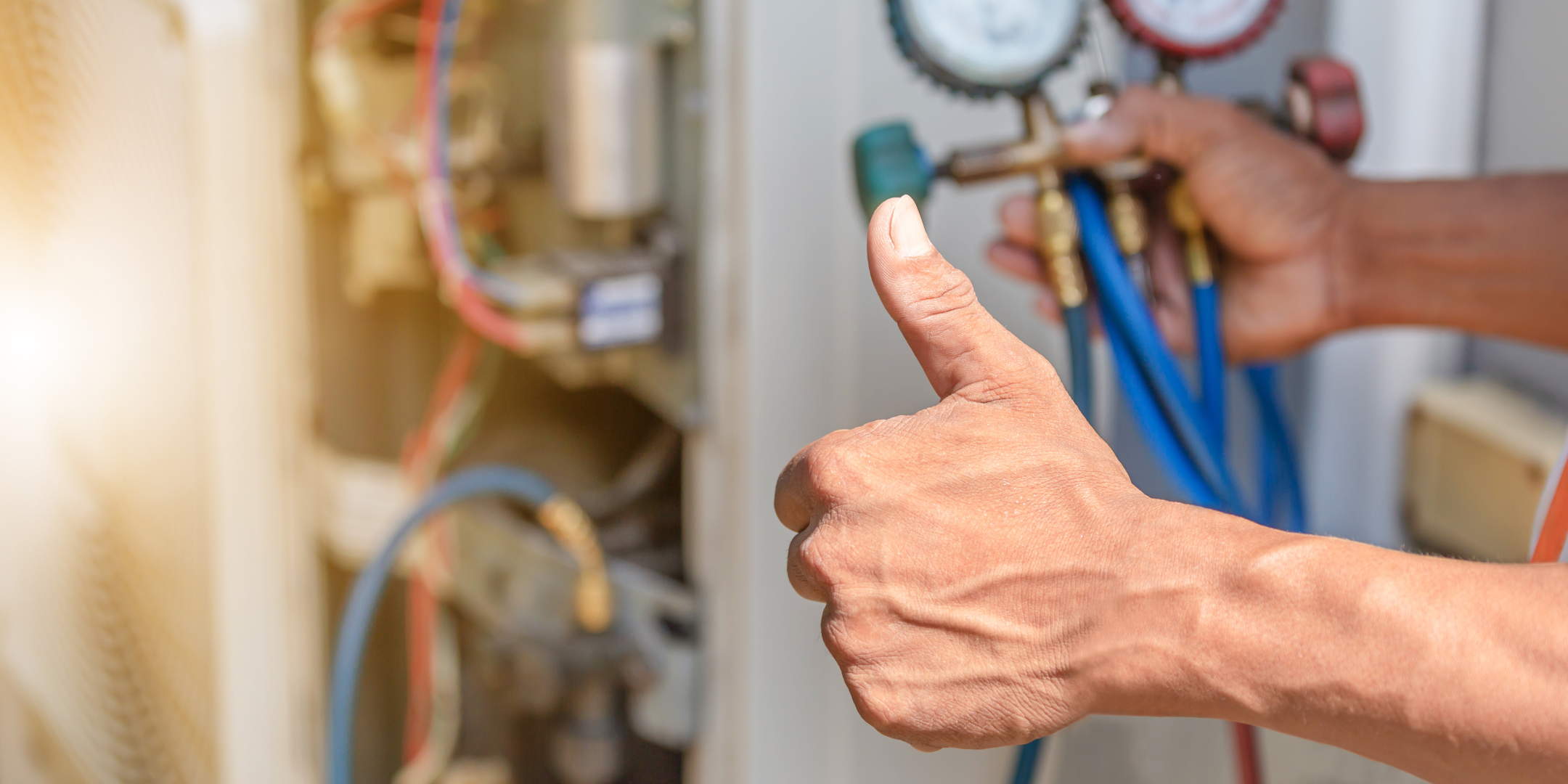 Man with his thumb up in the foreground, HVAC calibration equipment in the background, slightly blurred.